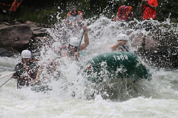 People in a raft rowing thru white water